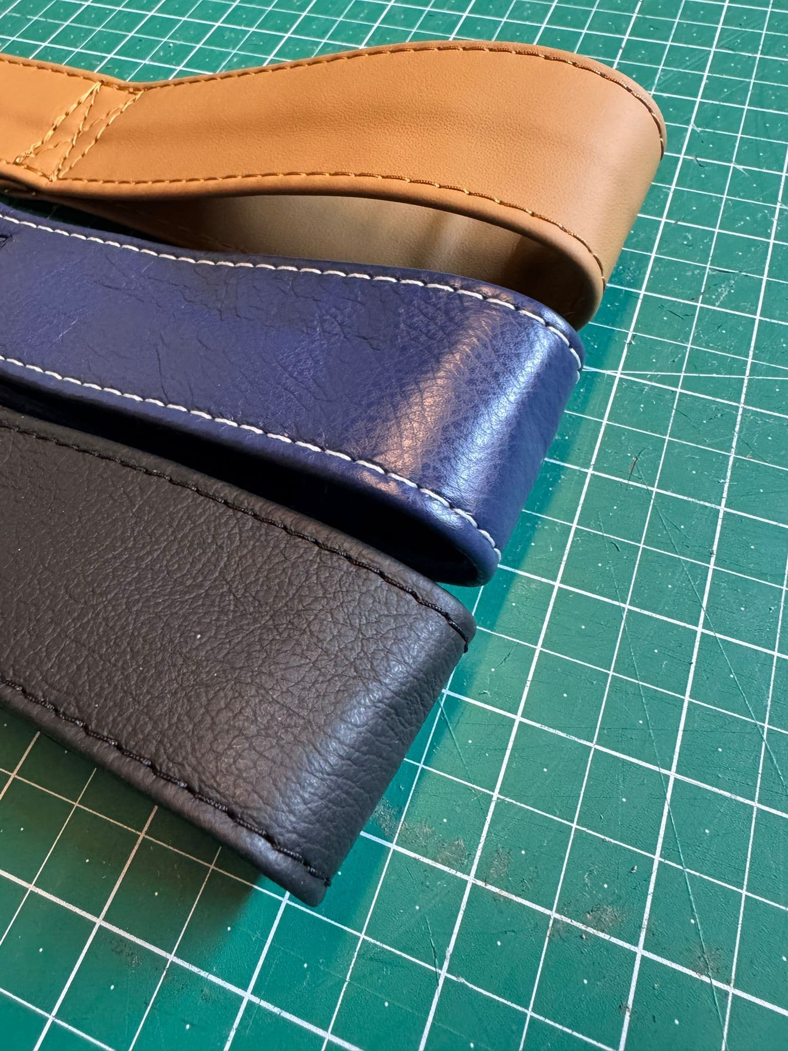 Leather piping strips in tan, blue and black on cutting mat