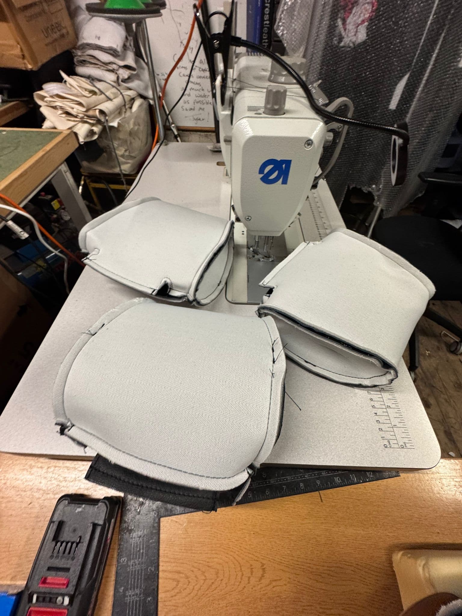 Industrial sewing machine stitching white fabric panels